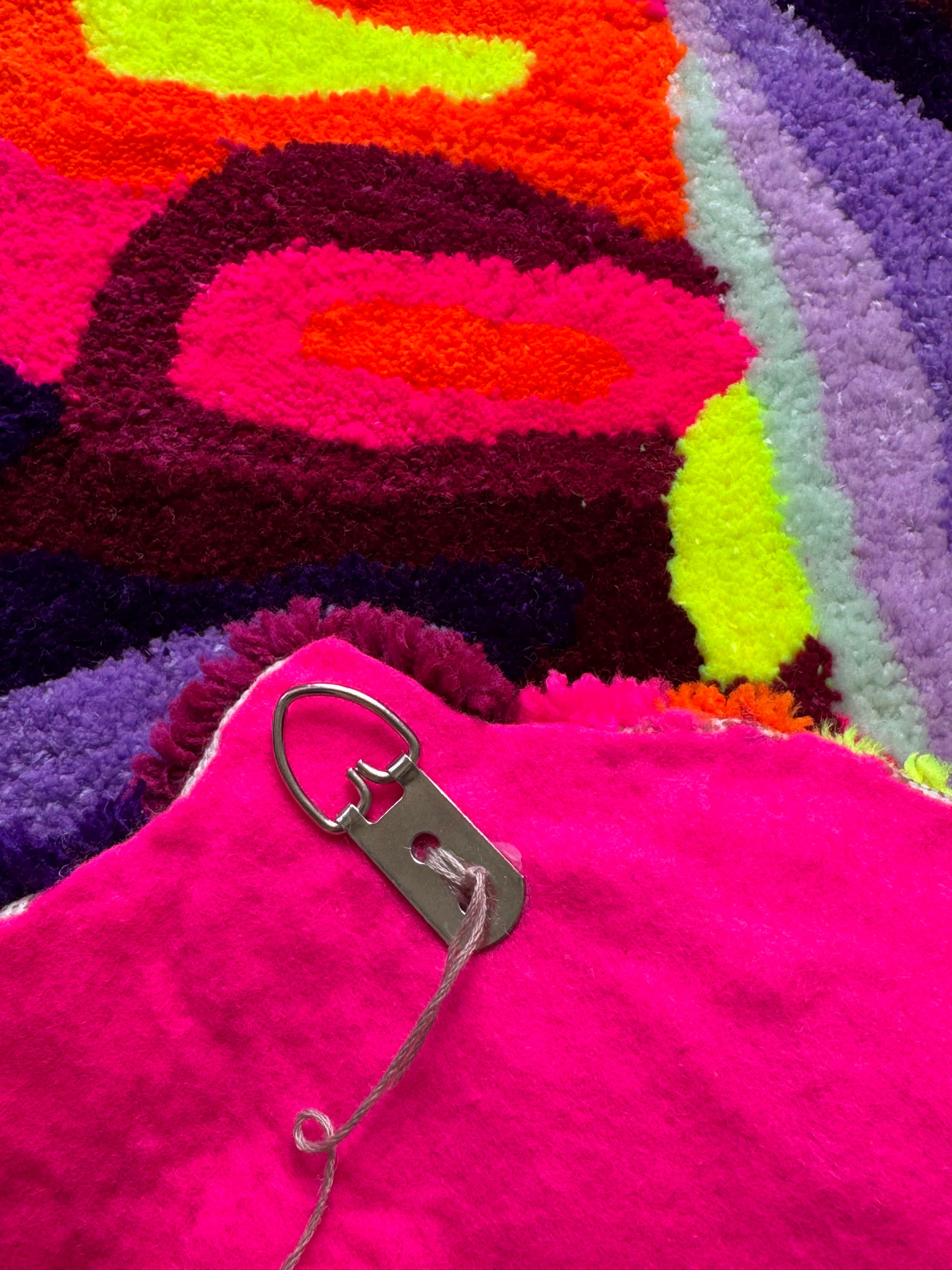 Close-up of a colorful textured fabric with a metal clip attached.