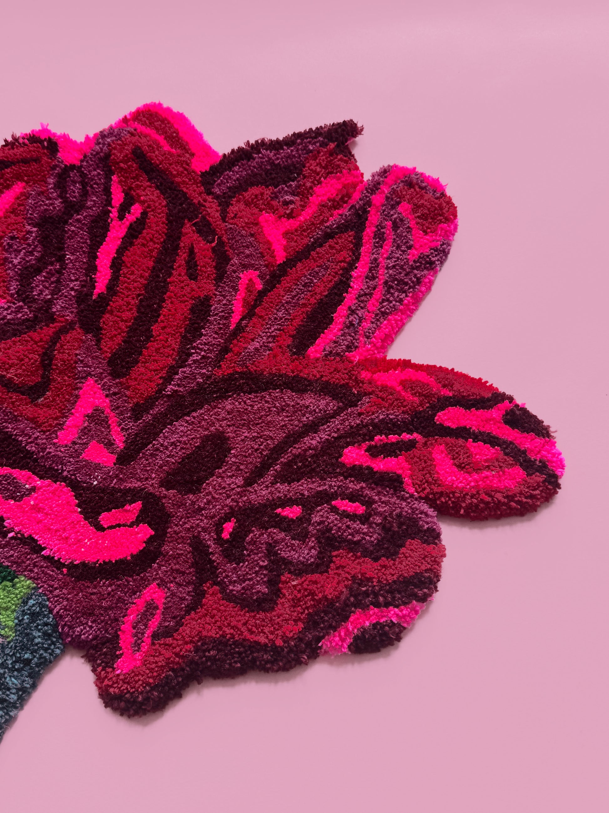 Close-up of a textured pink and red flower rug on a pink background