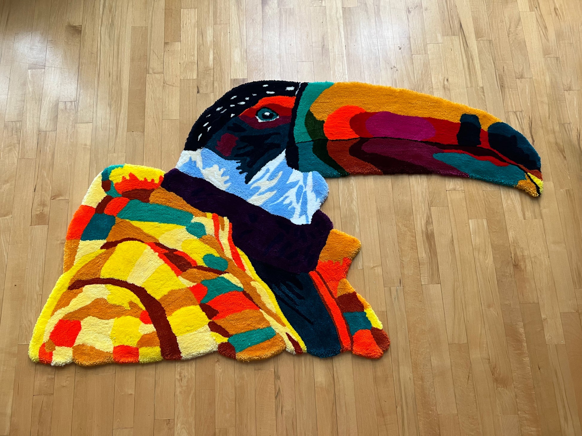 Colorful toucan-shaped rug on a wooden floor