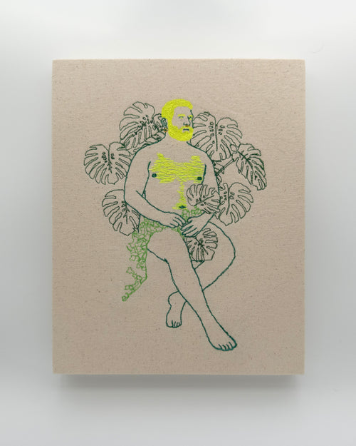 Amarelo: embroidered figure with a neon yellow beard, legs crossed, framed by monstera leaves, on natural canvas