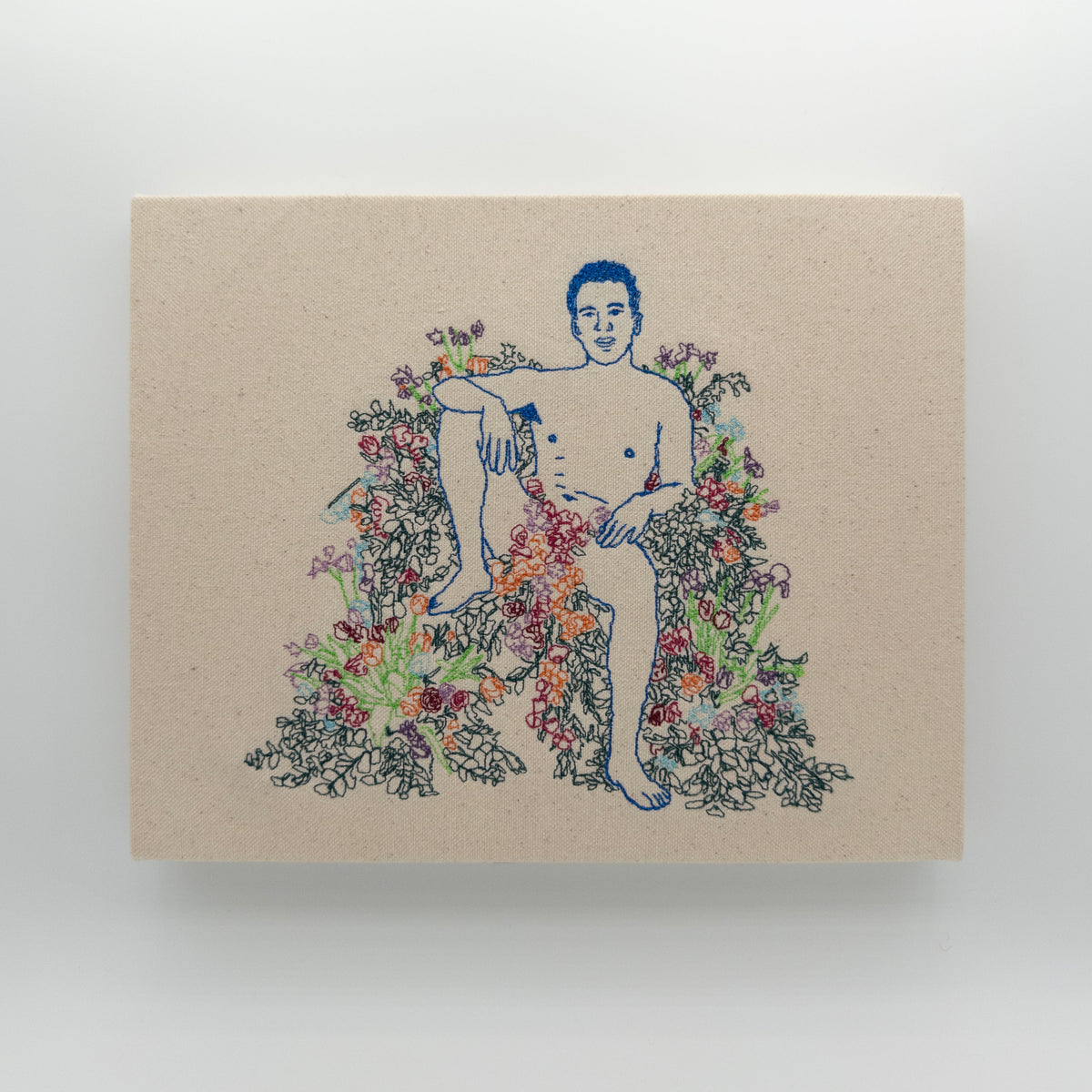 Azul: embroidered figure outlined in royal blue, seated with one knee up among flowers, on natural canvas